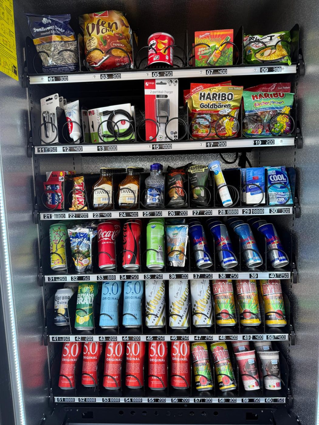 Automat vor dem Haus mit Getränken, Snacks, Süßwaren, Ladekabeln und Hygieneartikeln